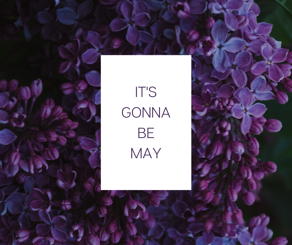 black text on a white background that reads "it's gonna be May," with purple lilacs in the background